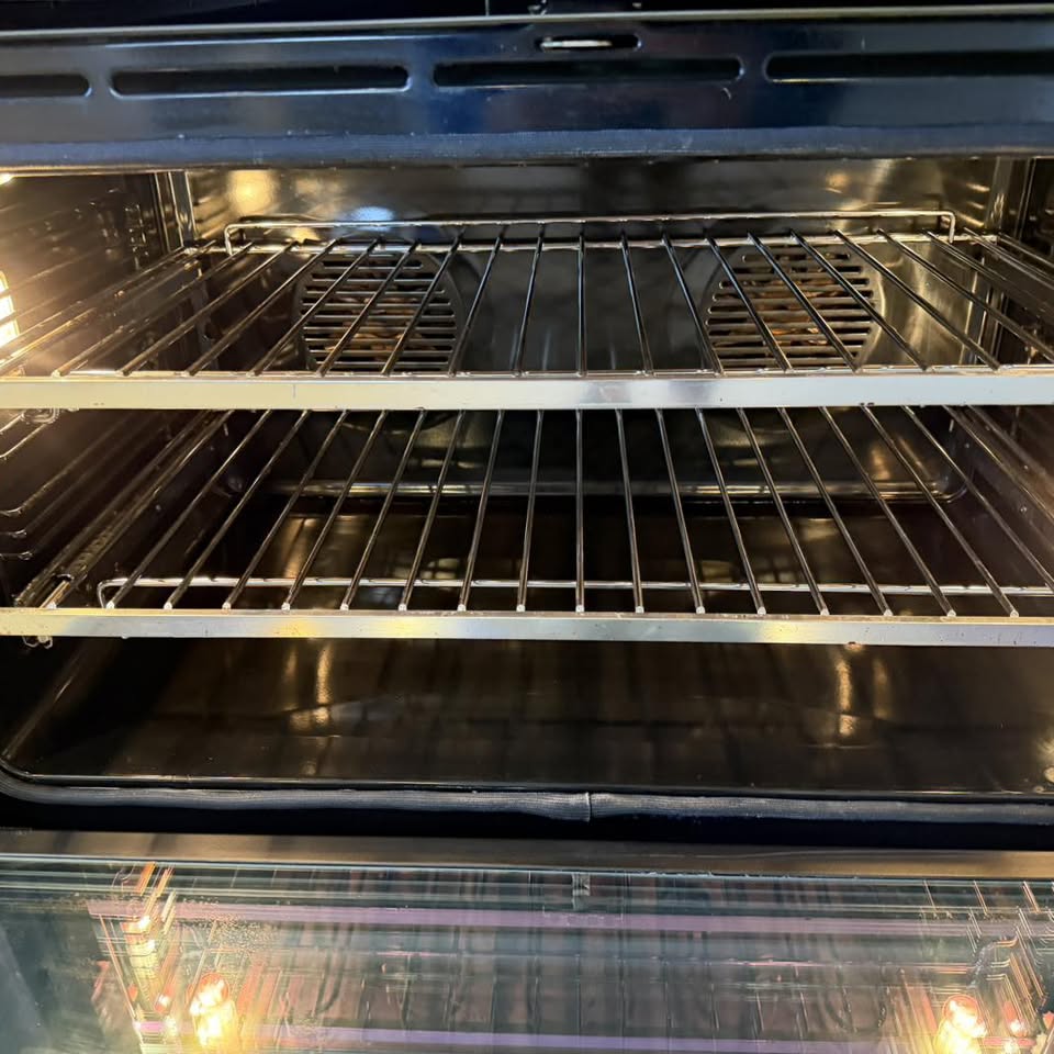Oven cavity with gleaming black enamel and polished racks after deep clean