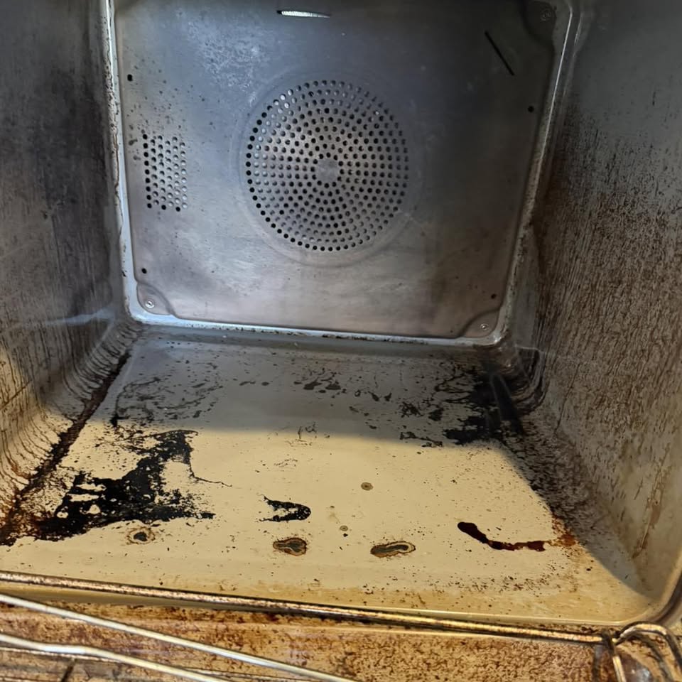 Heavily burnt oven cavity with blackened grease before professional cleaning