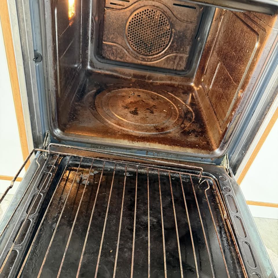 Severely burnt oven interior with carbonised racks before deep cleaning